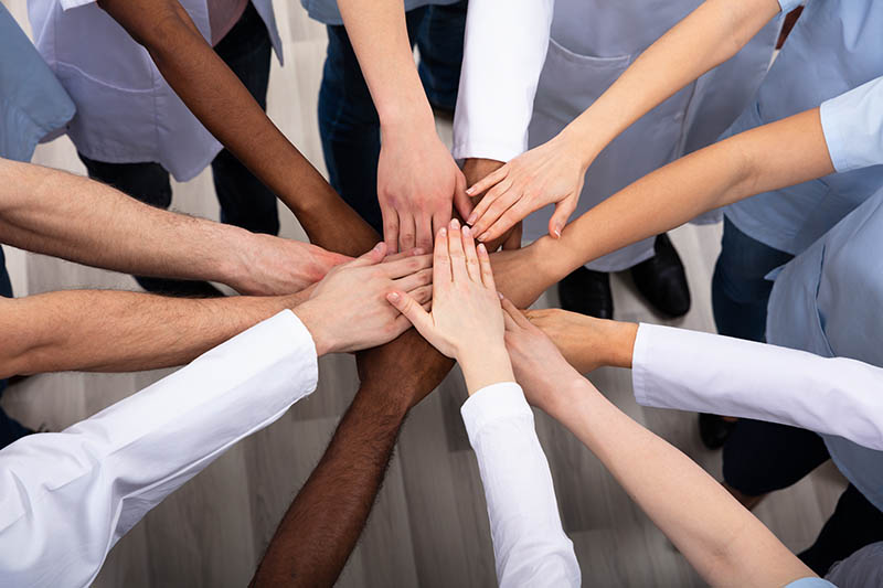 Elevated View Of Doctors Stacking Hands strategic diversity inclusion consulting & training